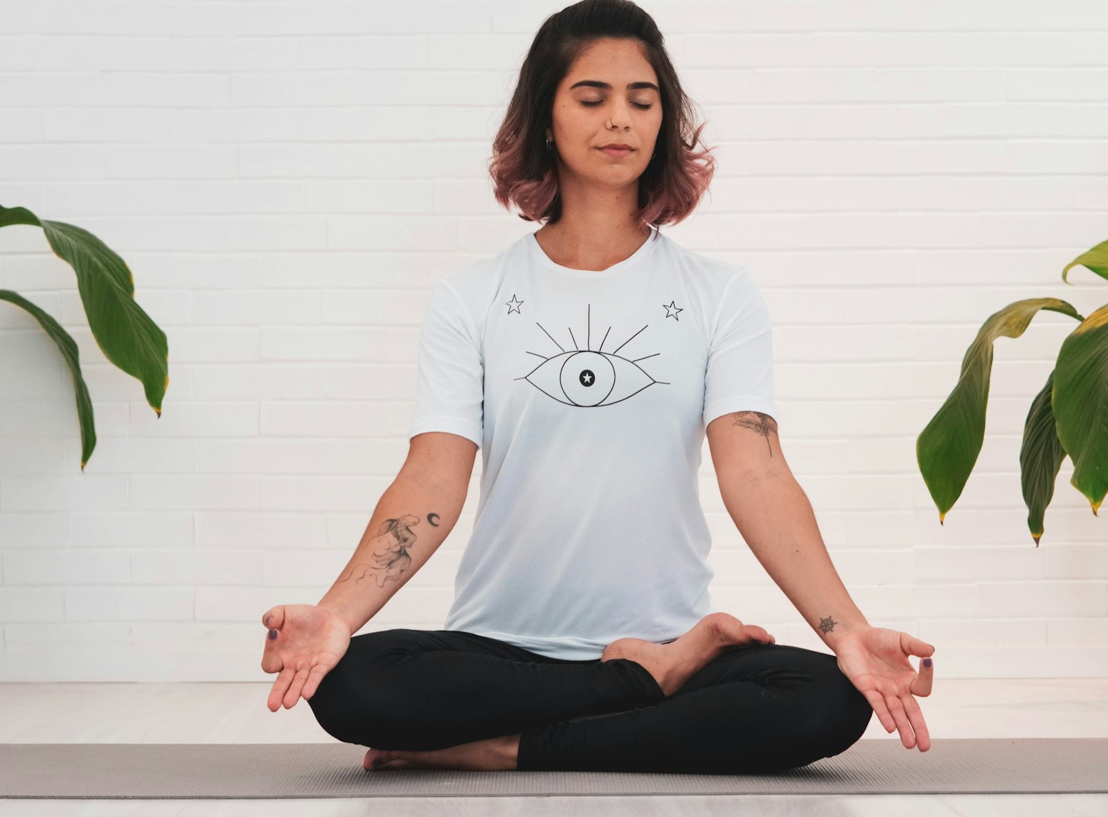 Photo by Lutchenca Medeiros woman in white crew neck t-shirt and black pants sitting on white table